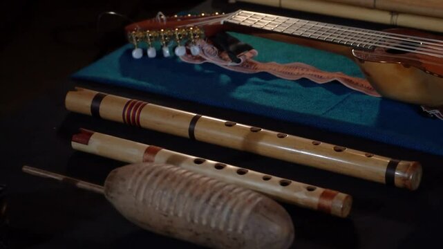 Close-up of Andean instruments like charango, wooden flutes, and percussion on textile.
