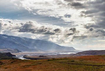 Breathtaking Landscape of Rolling Hills and Majestic Mountains with a Dramatic Sky Above: Nature's Splendor at Dusk Captured in Iceland's Scenic Beauty