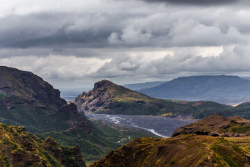 A Scenic View of Majestic Mountains and a Serene River Flowing Through a Lush Valley Under a Dramatic Sky Full of Clouds and Nature's Breathtaking Beauty