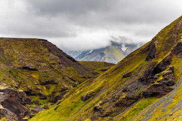 Breathtaking Icelandic Landscape: A Majestic View of Rolling Green Hills and Volcanic Rock Formations Under a Dramatic Cloud-Filled Sky