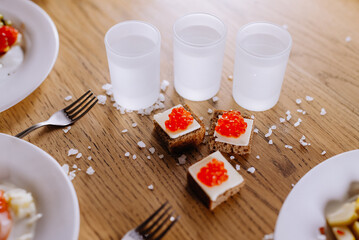 Delicious Appetizers with Red Caviar and Vodka on Wooden Table