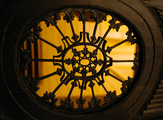 A stunning look at a detailed wrought iron pattern with warm yellow lighting glowing in the background, enhancing the artistic elements.