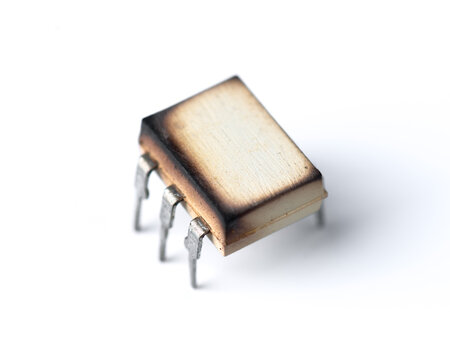 Close-up of a burnt integrated circuit on a white background