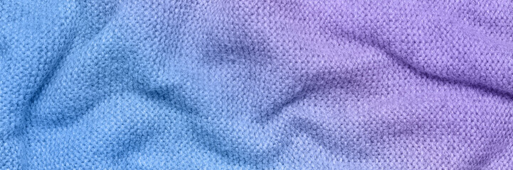 A soft and textured gradient blue and purple knitted fabric with gentle waves and folds, creating a cozy and warm appearance. Ideal for textile backgrounds, fashion, or home decor themes.
