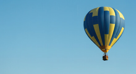Fototapeta premium Colorful Hot Air Balloon Drifting in Blue Sky Over Scenic Landscape