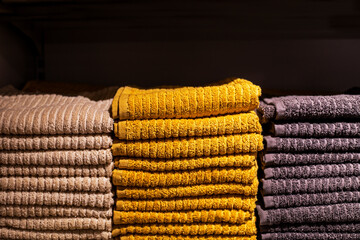 beige, yellow and blue towels stacked on shelves