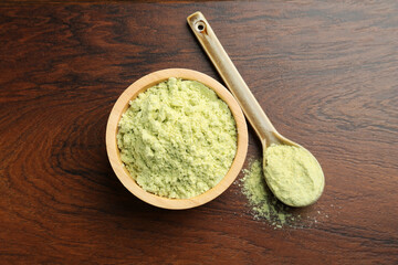 Dry wasabi powder in bowl and spoon on wooden table, top view