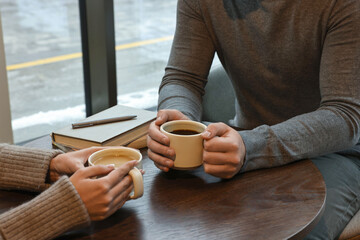 Colleagues having coffee break at wooden table in cafe, closeup