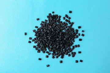 Pile of black plastic granules on light blue background, top view
