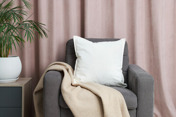 Blank soft pillow on cozy armchair at home