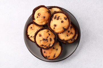 Delicious muffin with chocolate chips on light grey table, top view