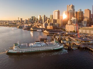 Seattle ferry docks at sunset. Ferry departing from waterfront, city skyline in background. Golden hour light. Waterfront, Seattle, Washington, USA