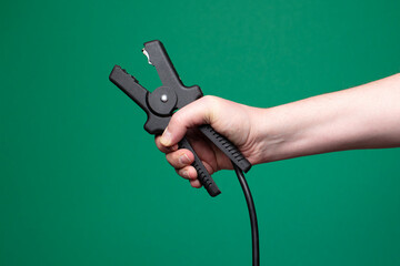 Close-up of jumper cables in hand, clean green background.
