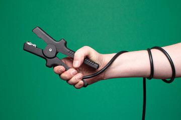Close up of hand holding a jumper cable (minus pole), studio, green background. Copy space. 
