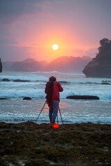 Photographer on the beach at sunset in Java Indonesia Ngliyep beach
