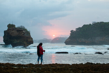 Photographer on the beach at sunset in Java Indonesia Ngliyep beach