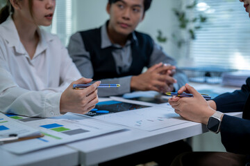 Three people are sitting at a table with pens and papers in front of them