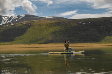 A man swims sitting on a chair on a boat on a lake with a view of a hill and a blue sky. First time...