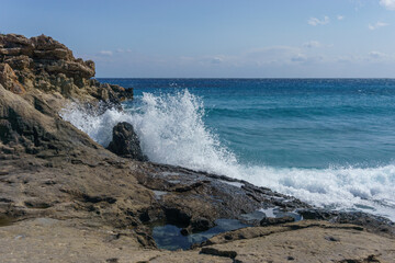 Sea water splashes at petrified tree at Geopark of Agios Nikolaos a Petrified Forest at mediterranean sea coast, Laconia, Peloponnese, Greece