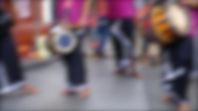 A blurry background image with vibrant colors, showing people in a dynamic setting, possibly engaging in a cultural or social activity indoors.