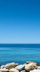 Vibrant Blue Ocean Scene with Rocks and Clear Sky