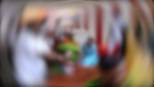 A blurry background image with vibrant colors, showing people in a dynamic setting, possibly engaging in a cultural or social activity indoors.