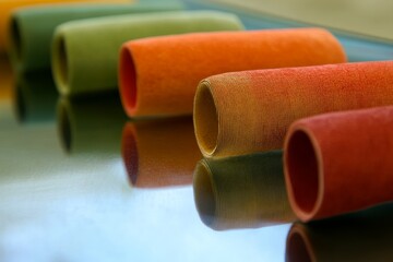 Colorful Rolled Fabrics on Glass Surface with Reflections