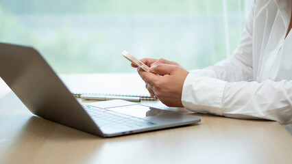 Close up of a young Asian woman hands holding and using a mobile smartphone.