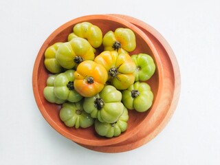 Ranti tomatoes in a wooden plate on a white background.