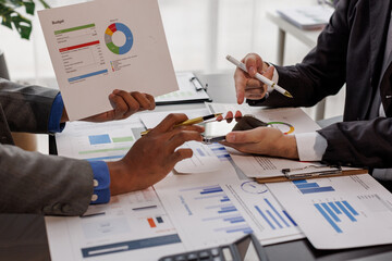 Team of confident business people point to graphs and charts to analyze market data, balance sheet,...