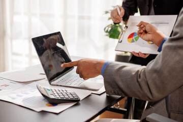 Team of confident business people point to graphs and charts to analyze market data, balance sheet, account, net profit to plan new sales strategies to increase production capacity.
