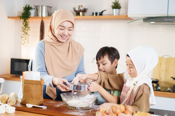 Asian muslim woman and lovely children are preparing and cooking in the kitchen.