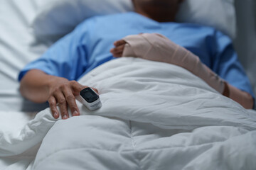 Patient wearing pulse oximeter and resting in hospital bed