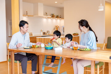 リビングで朝ごはんを食べる四人家族