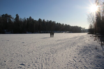 Celestial Chill: A Frozen River’s Glacial Beauty Under Winter’s Golden Gaze and walking pair