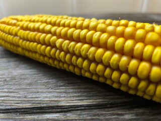 Beautiful juicy yellow corn lies on a wooden table. Close-up
