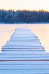 Obraz premium sparkling frost on wooden path leading through winter forest with first rays of sunlight filtering through
