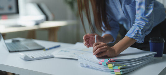 Businesswoman organizing a large stack of paperwork with colorful sticky notes, working diligently...