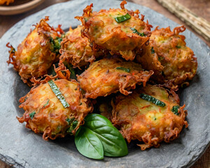 This image showcases a plate of crispy, golden-brown vegetable fritters garnished with fresh cilantro leaves. 
