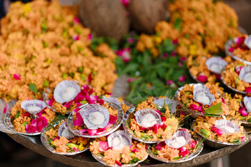 Floral offering plates with marigold flowers, rose petals, and cotton wicks, prepared for religious rituals at the Ganges River in Varanasi, India.