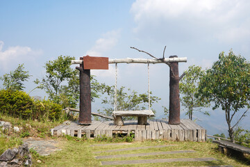 A wooden swing on a mountaintop on a clear day.
