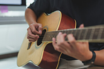 Fototapeta premium Close-up view of a musician skillfully playing an acoustic guitar, fingers deftly navigating the strings while creating beautiful melodies in a cozy home studio environment