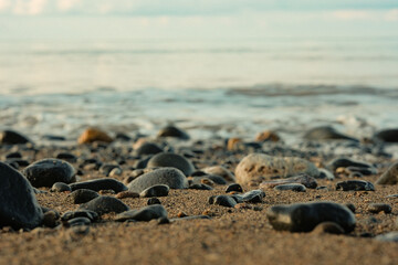 View of the beach with waves crashing on the sand and rocks at dusk