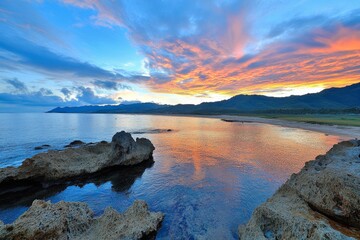 Obraz premium A panoramic view of an island sunrise, with the ocean glowing in warm orange and pink tones