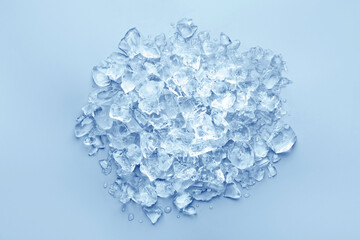 Pieces of crushed ice on light blue background, top view