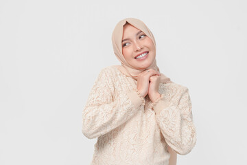 Excited young Asian Muslim woman wearing headscarf smiling to the camera.