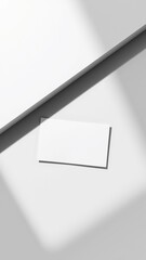 Minimalist design featuring a blank business card on a light-colored surface with shadows enhancing the composition