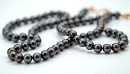 Obraz premium Close-up of black pearl necklace on white background. Luxury jewelry shot features elegance, wealth, glamour. Ideal gift for woman. Bracelet made of pearls. Elegant female fashion accessory.