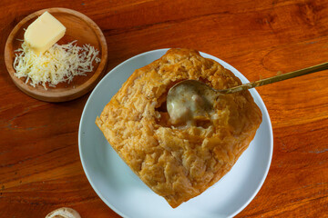 Zuppa toscana, minestra di pane, or zuppa soup in Indonesian. A creamy soup made with milk and cheese, added with chicken and sliced mushroom, also square puff pastry on top. Served on wooden table