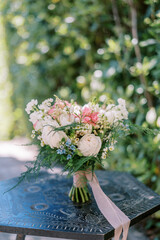 Wedding bouquet stands on a wooden carved table in a green garden